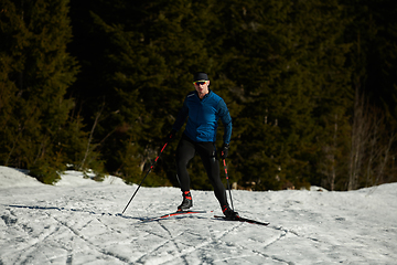 Image showing Nordic skiing or Cross-country skiing classic technique practiced by man in a beautiful panoramic trail at morning.Selective focus.