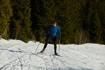 Image showing Nordic skiing or Cross-country skiing classic technique practiced by man in a beautiful panoramic trail at morning.Selective focus.