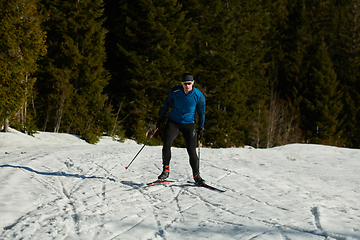 Image showing Nordic skiing or Cross-country skiing classic technique practiced by man in a beautiful panoramic trail at morning.Selective focus.