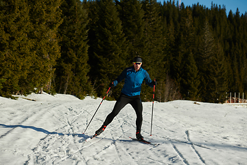 Image showing Nordic skiing or Cross-country skiing classic technique practiced by man in a beautiful panoramic trail at morning.Selective focus.