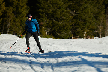 Image showing Nordic skiing or Cross-country skiing classic technique practiced by man in a beautiful panoramic trail at morning.Selective focus.