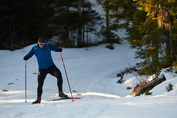 Image showing Nordic skiing or Cross-country skiing classic technique practiced by man in a beautiful panoramic trail at morning.Selective focus.