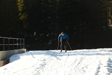 Image showing Nordic skiing or Cross-country skiing classic technique practiced by man in a beautiful panoramic trail at morning.Selective focus.