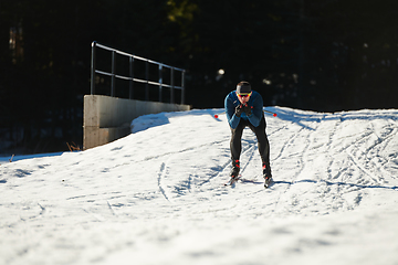 Image showing Nordic skiing or Cross-country skiing classic technique practiced by man in a beautiful panoramic trail at morning.Selective focus.