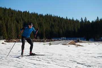 Image showing Nordic skiing or Cross-country skiing classic technique practiced by man in a beautiful panoramic trail at morning.Selective focus.