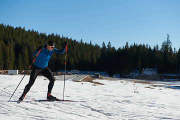 Image showing Nordic skiing or Cross-country skiing classic technique practiced by man in a beautiful panoramic trail at morning.Selective focus.