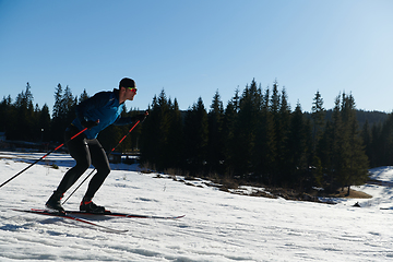 Image showing Nordic skiing or Cross-country skiing classic technique practiced by man in a beautiful panoramic trail at morning.Selective focus.