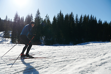 Image showing Nordic skiing or Cross-country skiing classic technique practiced by man in a beautiful panoramic trail at morning.Selective focus.