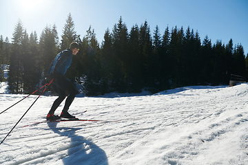 Image showing Nordic skiing or Cross-country skiing classic technique practiced by man in a beautiful panoramic trail at morning.Selective focus.