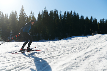 Image showing Nordic skiing or Cross-country skiing classic technique practiced by man in a beautiful panoramic trail at morning.Selective focus.