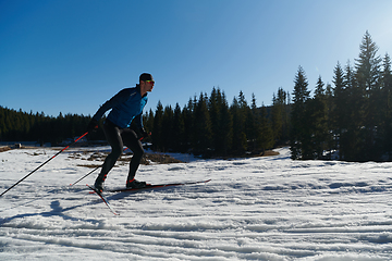 Image showing Nordic skiing or Cross-country skiing classic technique practiced by man in a beautiful panoramic trail at morning.Selective focus.