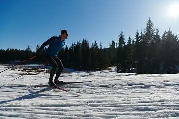 Image showing Nordic skiing or Cross-country skiing classic technique practiced by man in a beautiful panoramic trail at morning.Selective focus.