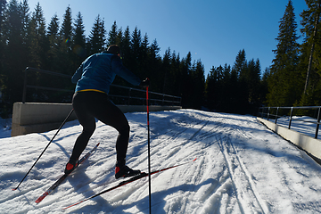 Image showing Nordic skiing or Cross-country skiing classic technique practiced by man in a beautiful panoramic trail at morning.Selective focus.