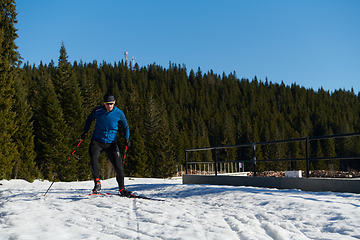 Image showing Nordic skiing or Cross-country skiing classic technique practiced by man in a beautiful panoramic trail at morning.Selective focus.