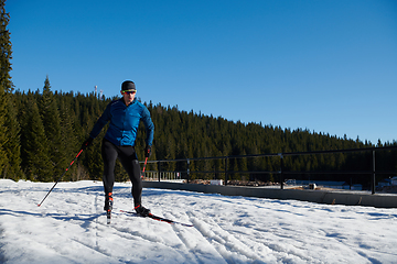 Image showing Nordic skiing or Cross-country skiing classic technique practiced by man in a beautiful panoramic trail at morning.Selective focus.