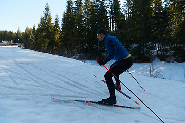 Image showing Nordic skiing or Cross-country skiing classic technique practiced by man in a beautiful panoramic trail at morning.Selective focus.