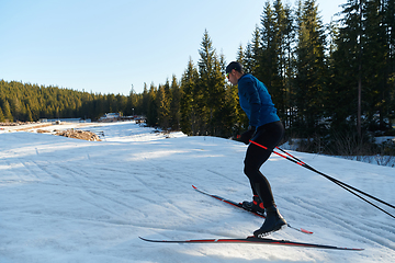 Image showing Nordic skiing or Cross-country skiing classic technique practiced by man in a beautiful panoramic trail at morning.Selective focus.