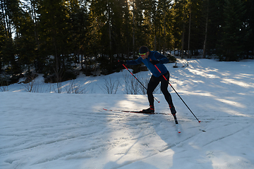 Image showing Nordic skiing or Cross-country skiing classic technique practiced by man in a beautiful panoramic trail at morning.Selective focus.