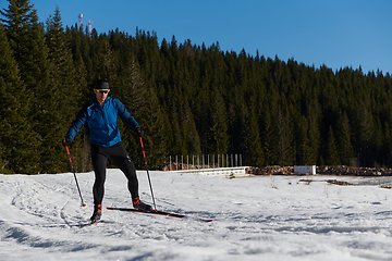 Image showing Nordic skiing or Cross-country skiing classic technique practiced by man in a beautiful panoramic trail at morning.Selective focus.