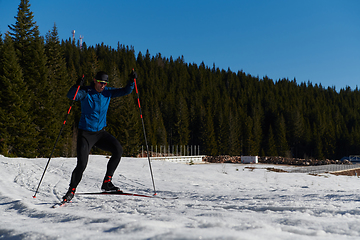 Image showing Nordic skiing or Cross-country skiing classic technique practiced by man in a beautiful panoramic trail at morning.Selective focus.