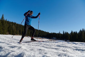 Image showing Nordic skiing or Cross-country skiing classic technique practiced by man in a beautiful panoramic trail at morning.Selective focus.