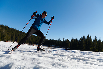 Image showing Nordic skiing or Cross-country skiing classic technique practiced by man in a beautiful panoramic trail at morning.Selective focus.