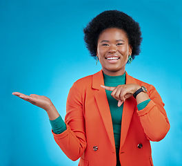 Image showing Happy black woman, portrait and pointing to palm for advertising against a blue studio background. Face of African female person show advertisement in marketing, list or sale discount on mockup space