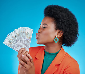 Image showing Cash, kiss and a black woman lottery winner on a blue background in studio holding money for finance. Savings, investment or economy growth with a young female person posing for financial freedom