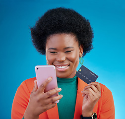 Image showing Black woman, credit card and phone in studio, smile or thinking for choice, ecommerce and blue background. Gen z African girl, smartphone and fintech app for payment, cybersecurity or online shopping