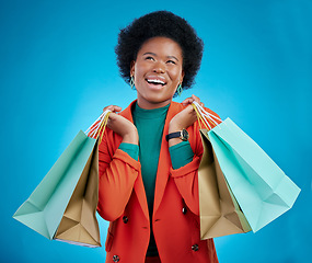 Image showing Shopping bag, thinking portrait and woman for fashion discount, giveaway wow or retail sales on blue background. Happy, excited and clothes inspiration of customer, winner or african person in studio