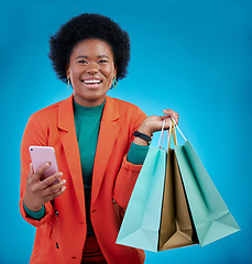 Image showing Shopping bag, phone and happy woman for e commerce sale, discount or social media on blue background. Portrait, mobile blog and fashion of african person, customer or online user with gift in studio