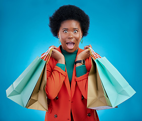 Image showing Shopping bag, wow portrait and woman for fashion discount, giveaway or retail sales on blue background. Happy, excited or surprise face of customer, winner or african person in clothes deal in studio