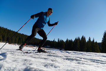 Image showing Nordic skiing or Cross-country skiing classic technique practiced by man in a beautiful panoramic trail at morning.Selective focus.