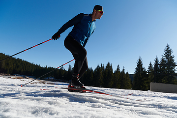 Image showing Nordic skiing or Cross-country skiing classic technique practiced by man in a beautiful panoramic trail at morning.Selective focus.