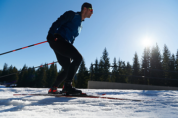 Image showing Nordic skiing or Cross-country skiing classic technique practiced by man in a beautiful panoramic trail at morning.Selective focus.