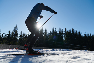 Image showing Nordic skiing or Cross-country skiing classic technique practiced by man in a beautiful panoramic trail at morning.Selective focus.