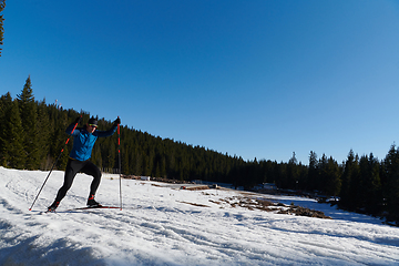 Image showing Nordic skiing or Cross-country skiing classic technique practiced by man in a beautiful panoramic trail at morning.Selective focus.