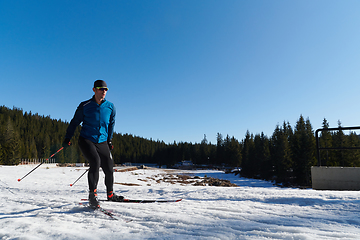 Image showing Nordic skiing or Cross-country skiing classic technique practiced by man in a beautiful panoramic trail at morning.Selective focus.