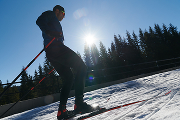 Image showing Nordic skiing or Cross-country skiing classic technique practiced by man in a beautiful panoramic trail at morning.Selective focus.