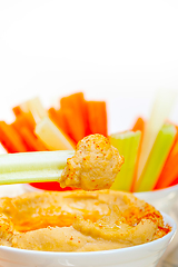 Image showing fresh hummus dip with raw carrot and celery