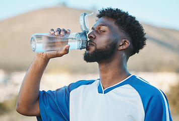 Image showing Black man, fitness or soccer player drinking water in training, exercise or workout in football field. Thirsty, sports or tired athlete on resting break with a healthy beverage for energy to relax