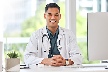 Image showing Happy, portrait of man and doctor at table in hospital for healthcare, insurance or wellness. Face, medical professional and confident surgeon at desk, expert smile and employee from Brazil in clinic