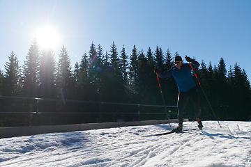 Image showing Nordic skiing or Cross-country skiing classic technique practiced by man in a beautiful panoramic trail at morning.Selective focus.