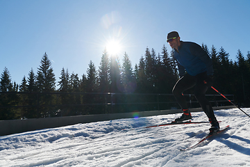 Image showing Nordic skiing or Cross-country skiing classic technique practiced by man in a beautiful panoramic trail at morning.Selective focus.