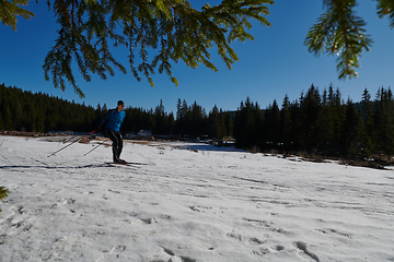 Image showing Nordic skiing or Cross-country skiing classic technique practiced by man in a beautiful panoramic trail at morning.Selective focus.