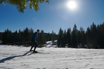 Image showing Nordic skiing or Cross-country skiing classic technique practiced by man in a beautiful panoramic trail at morning.Selective focus.