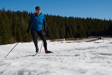 Image showing Nordic skiing or Cross-country skiing classic technique practiced by man in a beautiful panoramic trail at morning.Selective focus.