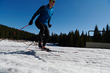 Image showing Nordic skiing or Cross-country skiing classic technique practiced by man in a beautiful panoramic trail at morning.Selective focus.