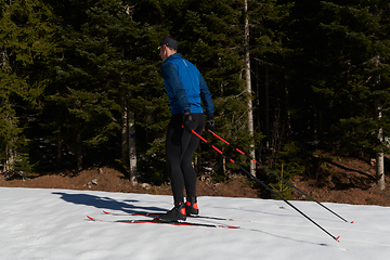 Image showing Nordic skiing or Cross-country skiing classic technique practiced by man in a beautiful panoramic trail at morning.Selective focus.