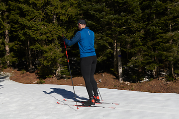 Image showing Nordic skiing or Cross-country skiing classic technique practiced by man in a beautiful panoramic trail at morning.Selective focus.